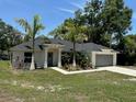 Attractive one-story house with a manicured lawn, tropical foliage, and two-car garage at 120 S Chandler Ave, Deland, FL 32724
