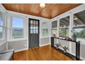 Bright sunroom featuring wood ceiling and floors, large windows, and a black entry door at 1407 Lantry Ct, Orlando, FL 32804