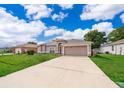 Inviting single-story home features a long driveway and attached two-car garage, under a bright blue sky at 142 Barrington Dr, Kissimmee, FL 34758