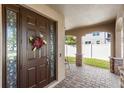 Charming front porch with brick flooring, decorative columns, and a welcoming entrance door at 15604 Starlite St, Clermont, FL 34714