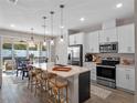 Modern kitchen boasts stainless steel appliances, white cabinets, a large island, and stylish pendant lighting at 31807 Broadwater Ave, Leesburg, FL 34748