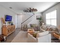 Comfortable living room features neutral tones, a decorative ceiling fan, and staircase access to upper level at 31807 Broadwater Ave, Leesburg, FL 34748