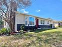 Well-manicured landscaping and inviting red door highlight this cozy home's exterior charm at 32803 Forest Ave, Leesburg, FL 34788