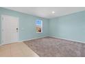 A bright, empty bedroom with neutral carpet and light blue walls showcases a window and tiled entryway at 520 Pinecrest Loop, Davenport, FL 33837