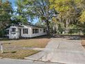 Inviting single-story home featuring a spacious driveway, mature trees, and a covered carport at 1208 Bonaire Dr, Leesburg, FL 34748