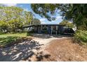 Front view of home with charming porch and mature trees, American flag, ample parking at 6013 Thames Way, Orlando, FL 32807