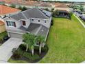 Aerial shot of a gray two-story home with large backyard, surrounded by neighborhood homes, a tile roof, and solar panels at 6049 Broad Oak Dr, Davenport, FL 33837