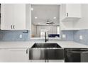 Close-up of a stainless steel undermount sink with a black faucet and blue tile backsplash at 122 Capri Dr, Davenport, FL 33897