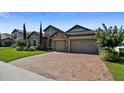 Charming stone home with a three-car garage, featuring a paved driveway and blossoming landscaping at 16736 Broadwater Ave, Winter Garden, FL 34787