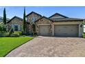 Attractive stone home with a three-car garage, surrounded by a lush green lawn and mature landscaping at 16736 Broadwater Ave, Winter Garden, FL 34787