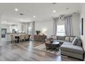 Spacious living room featuring wood floors, a comfortable sofa, and a dining room adjacent to the kitchen at 2258 Crystal Falls Way, Orlando, FL 32824