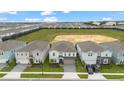 Aerial view of a neighborhood showcasing similar homes with neat landscaping, neutral tones, and a large open field beyond at 4321 Lana Avenue, Davenport, FL 33897