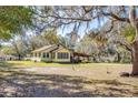 Exterior shot of a country home with a covered patio area and mature trees in the yard at 7438 Vivian Ln, Orlando, FL 32818