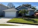 Charming single-story home showcasing a well-manicured lawn, and a two car garage on a sunny day at 938 Cherry Valley Way, Orlando, FL 32828