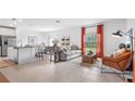 Open-concept living room with modern furniture, a kitchen island, and dining area, offering seamless flow at 128 Adventure Ave, Davenport, FL 33837