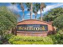 A brick community welcome sign with the gold lettered name, Westbrook, under palm trees at 1613 Priory Cir, Winter Garden, FL 34787