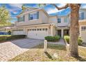 Attractive townhome featuring a two-car garage, brick paver driveway, and manicured front yard at 1613 Priory Cir, Winter Garden, FL 34787