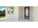 Inviting front entrance with a sleek black door, a welcome mat, and a well-lit porch area at 3036 Country Side Dr, Apopka, FL 32712