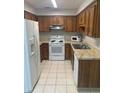 Functional kitchen with white appliances, tile floor and warm wood cabinets at 4655 Lighthouse Cir # 117, Orlando, FL 32808