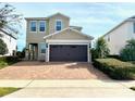 Charming two-story home with neutral colors, lush landscaping, and a brick driveway at 7479 Marker Ave, Kissimmee, FL 34747