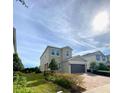 Charming two-story home showcasing a well-manicured front yard and a two-car garage, set against a sunny sky at 7479 Marker Ave, Kissimmee, FL 34747
