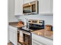 Close-up of the kitchen showcasing stainless steel appliances and gray countertops at 945 Laurel View Way, Groveland, FL 34736