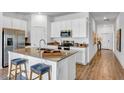 Bright kitchen featuring an island with seating, stainless steel appliances, and modern white cabinets at 945 Laurel View Way, Groveland, FL 34736