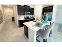Modern kitchen featuring sleek, dark cabinetry, stainless steel appliances and a bright breakfast bar at 945 Laurel View Way, Groveland, FL 34736