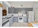Bright kitchen featuring gray cabinets, white appliances, and tile flooring at 165 Coralwood Cir, Kissimmee, FL 34743