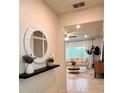 Bright entryway showcasing a round mirror, floating shelf with plants, and a glimpse into the living room at 17394 Million Lakes Ct, Clermont, FL 34714