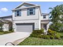 Charming two-story home featuring light gray siding, blue shutters, a two-car garage, and well-maintained landscaping at 17394 Million Lakes Ct, Clermont, FL 34714