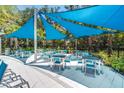 Community patio with many tables with chairs, covered by large blue canopies for shade at 2557 Shanti Dr, Kissimmee, FL 34746