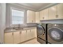 A functional laundry room with modern washer/dryer, ample cabinet space and a granite countertop with integrated stainless sink at 3227 S Crystal Lake Dr, Orlando, FL 32806