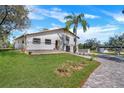 Charming home featuring a paved driveway, lush lawn, and mature landscaping under a bright blue sky at 40140 Swift Rd, Eustis, FL 32736