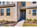 Inviting home entrance featuring a blue glass-paneled door, stone accents, and neatly landscaped garden beds at 2859 Bookmark Dr, Kissimmee, FL 34746