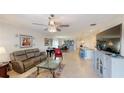 Open-concept living room with tile flooring, modern chandelier, tv, and lots of seating facing the open kitchen at 607 Black Eagle Dr, Groveland, FL 34736