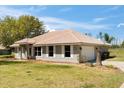 View of home with two-car garage, light gray exterior, white trim, tile roof and well-maintained lawn at 7847 Golf Paradise Way, Clermont, FL 34711