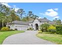 Stunning gray home with a tile roof, three-car garage, and lush landscaping on a circular driveway at 3340 Fernlake Pl, Longwood, FL 32779