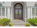 Elegant double front doors with decorative glass and sidelights, framed by white columns and manicured landscaping at 3340 Fernlake Pl, Longwood, FL 32779