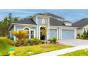 Charming two-story home features a blue exterior, paved driveway, and a three-car garage at 345 Aquamarine Way, Daytona Beach, FL 32124