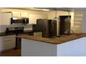 Open kitchen with stainless steel appliances, white cabinets, and a wooden breakfast bar at 4350 Perkinshire Ln # 108, Orlando, FL 32822