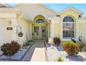 Inviting front porch with welcoming decor, decorative stone, hanging plants, and beautiful landscaping at 442 Troon Cir, Davenport, FL 33897