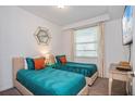 Bright bedroom with two twin beds, teal bedding, and modern decor, creating a comfortable and stylish space at 4751 Clock Tower Dr # 203, Kissimmee, FL 34746