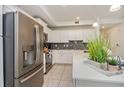 A well-lit kitchen features stainless steel appliances and light-colored cabinets with a gray backsplash at 4751 Clock Tower Dr # 203, Kissimmee, FL 34746