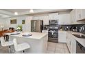Kitchen featuring stainless steel appliances, white cabinets, a gray backsplash, and a kitchen island with white seating at 4751 Clock Tower Dr # 203, Kissimmee, FL 34746