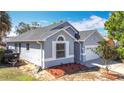 View of a one-story house with a dark roof and light gray walls, showing the front yard and landscaping at 6921 Blair Dr, Orlando, FL 32818