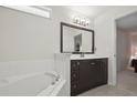 Bathroom features soaking tub, dark wood vanity, and a large mirror at 1740 Efland Ter, Deltona, FL 32738