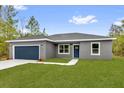 Beautiful home with a well-maintained lawn, a blue door, and a convenient two-car garage, creating a welcoming facade at 23 Fisher Run, Ocklawaha, FL 32179