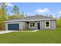 Inviting single-level home boasting a lush green lawn, stylish gray exterior, and a blue garage door, perfect for families at 23 Fisher Run, Ocklawaha, FL 32179