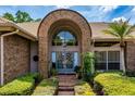 Home's entryway featuring a brick archway, double doors, and lush green landscaping at 2733 Deer Berry Ct, Longwood, FL 32779